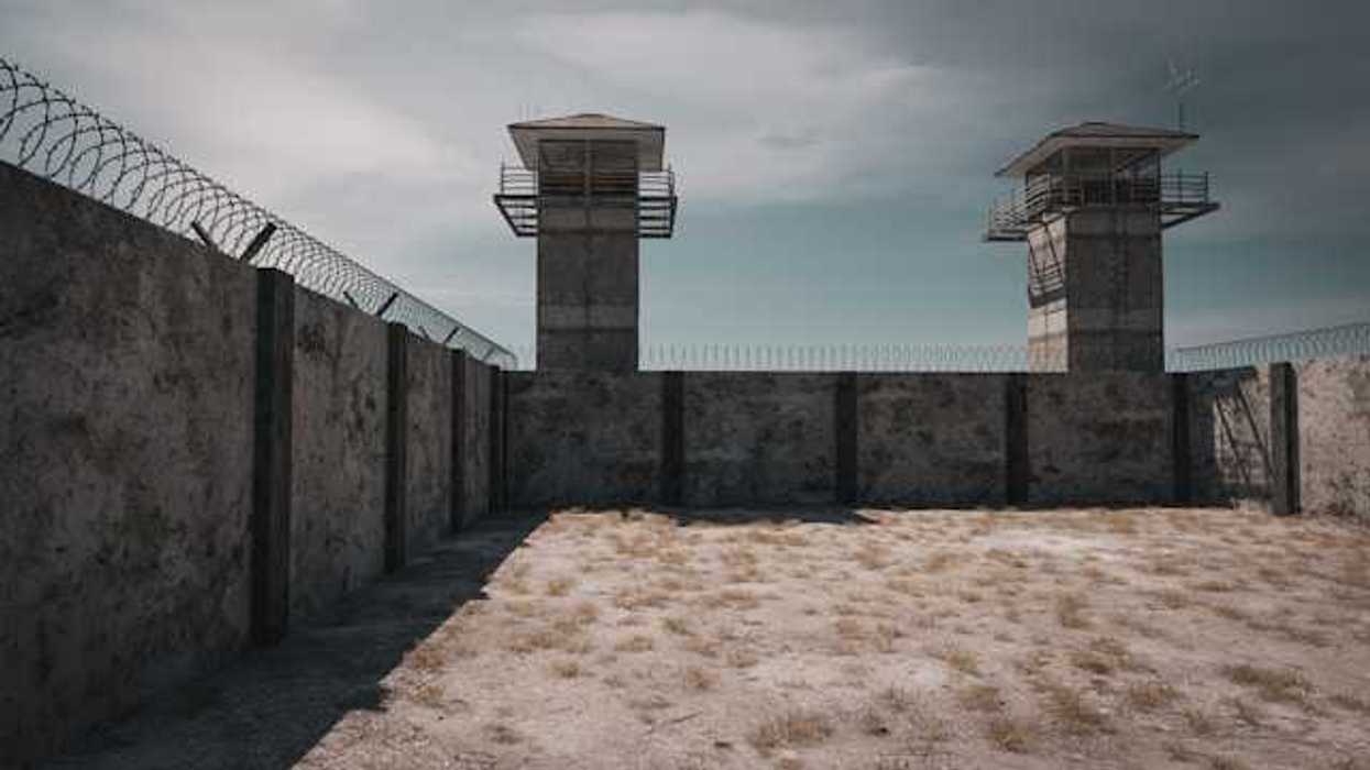 A prison wall with barbed wire and guard towers