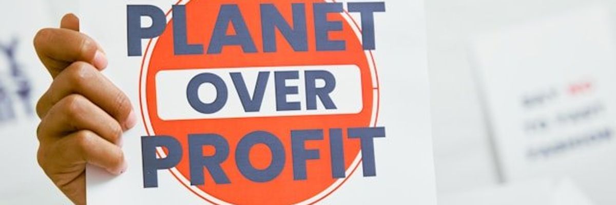 A protest sign that says Planet Over Profit.