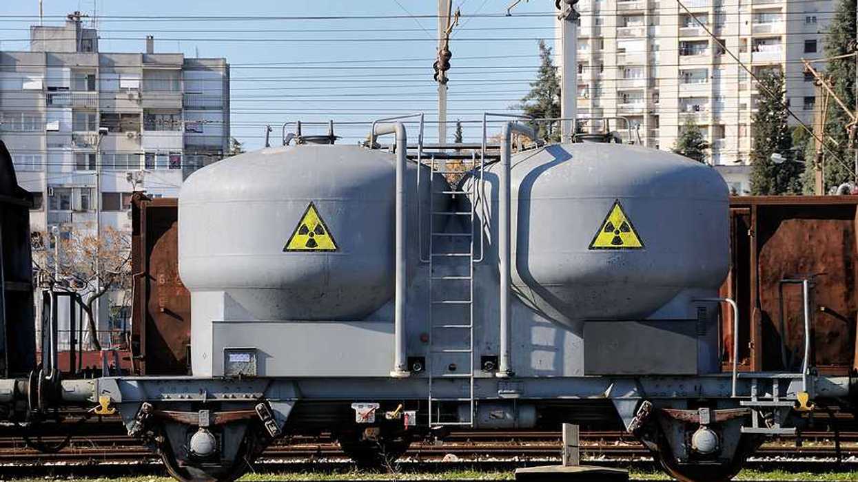 A rail car with yellow and black hazardous waste stickers on the side