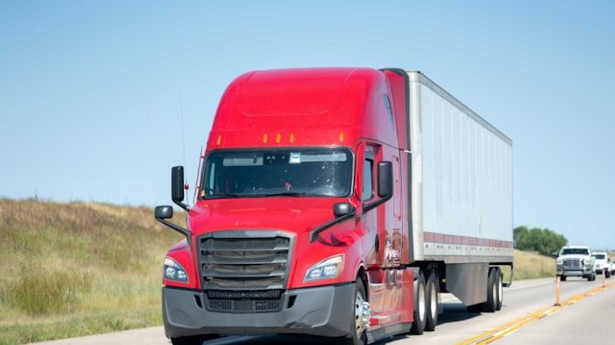 A red 18-wheeler truck on a highway.