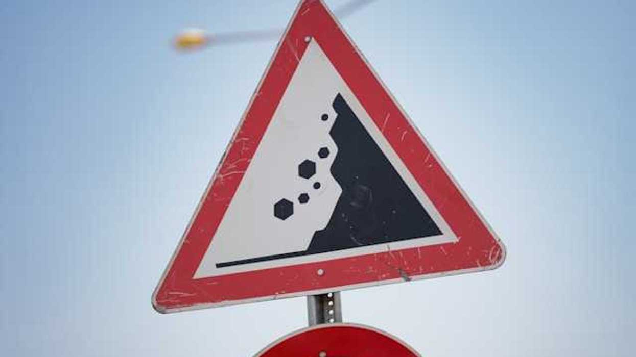 A red and black road sign warning of landslide danger