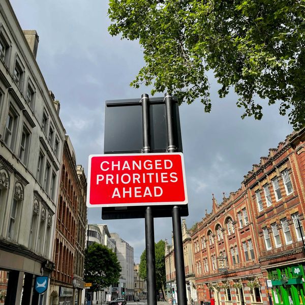 A red and white street sign saying Changed Priorities Ahead