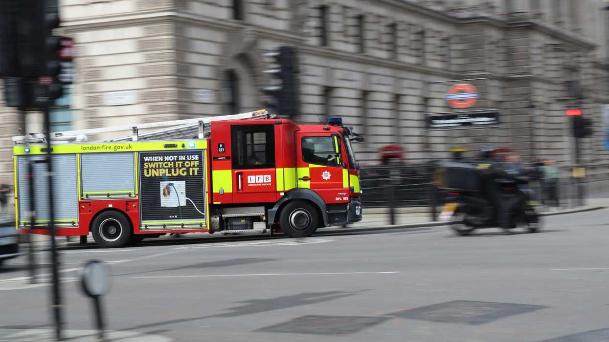 a red and yellow fire truck driving down a London street.