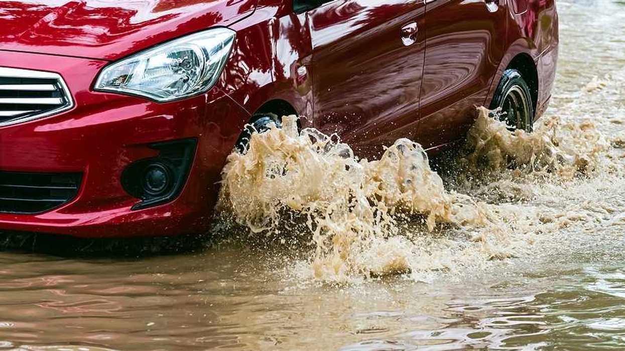 A red car driving through flood waters
