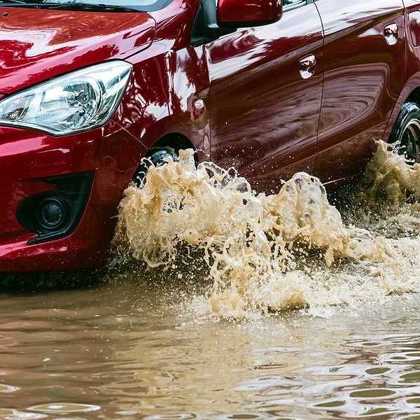 A red car driving through flood waters