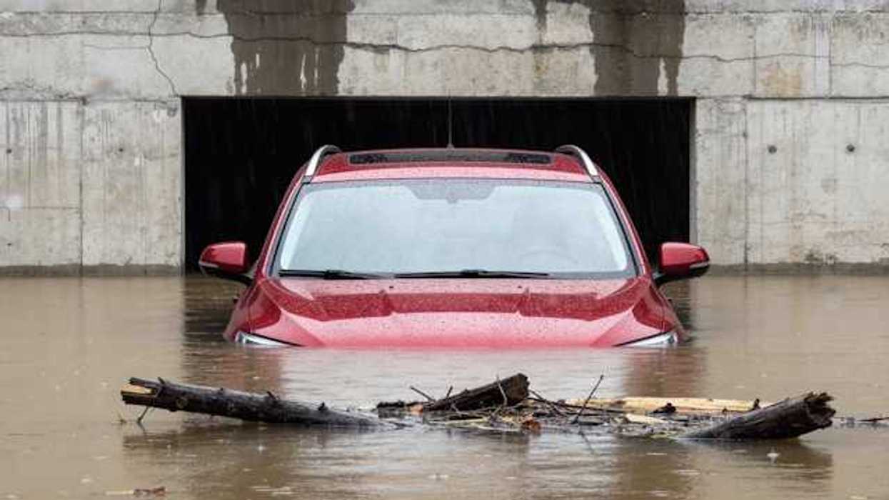 A red car submerged under flood waters