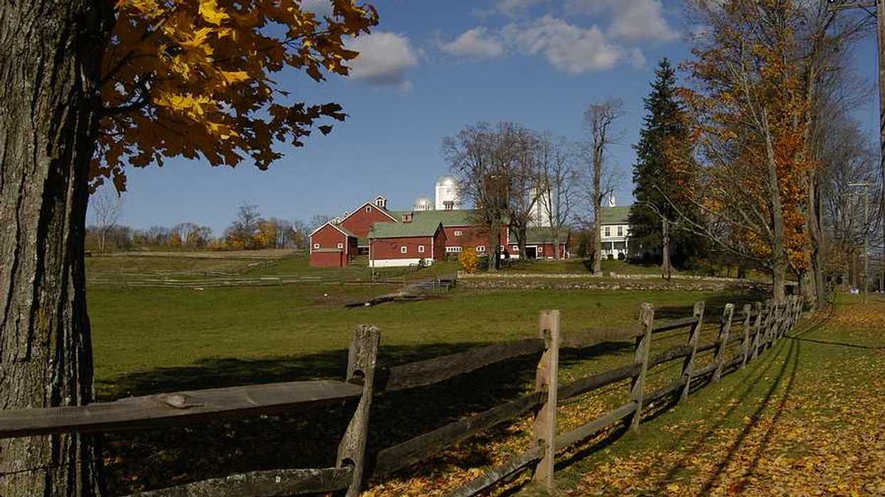 A red farmhouse with pastures in the foreground