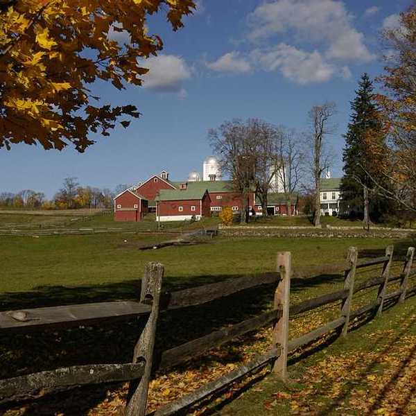 A red farmhouse with pastures in the foreground