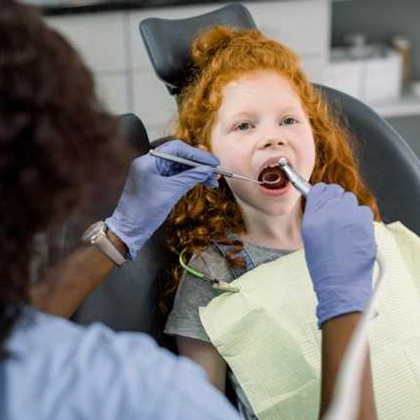 A red haired girl in a dentist's chair having her teeth examined