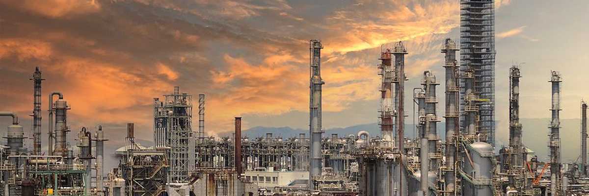 A refinery under a pink, cloud-strewn sky.