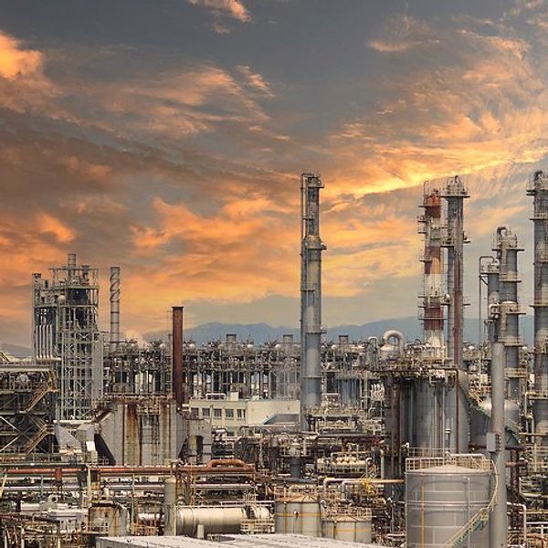 A refinery under a pink, cloud-strewn sky.