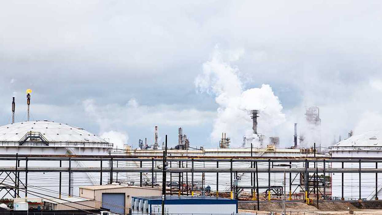 A refinery with white vats and smokestacks