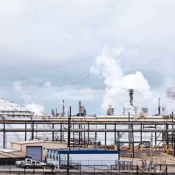 A refinery with white vats and smokestacks