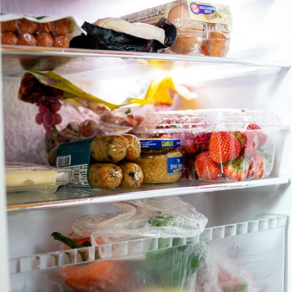 a refrigerator filled with lots of food and drinks wrapped in plastics.