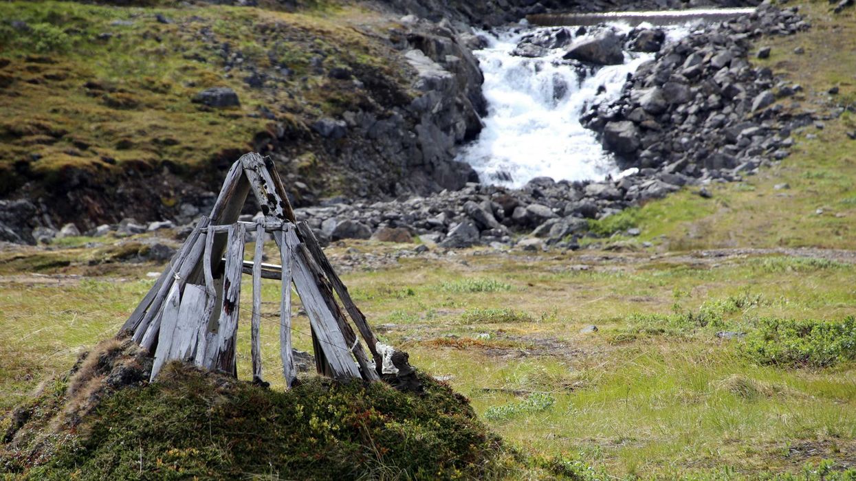 A river running through a green, rocky environment with a small wooden structure in foreground.