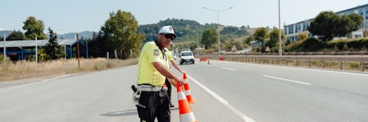 A road safety worker setting orange cones on a highway.