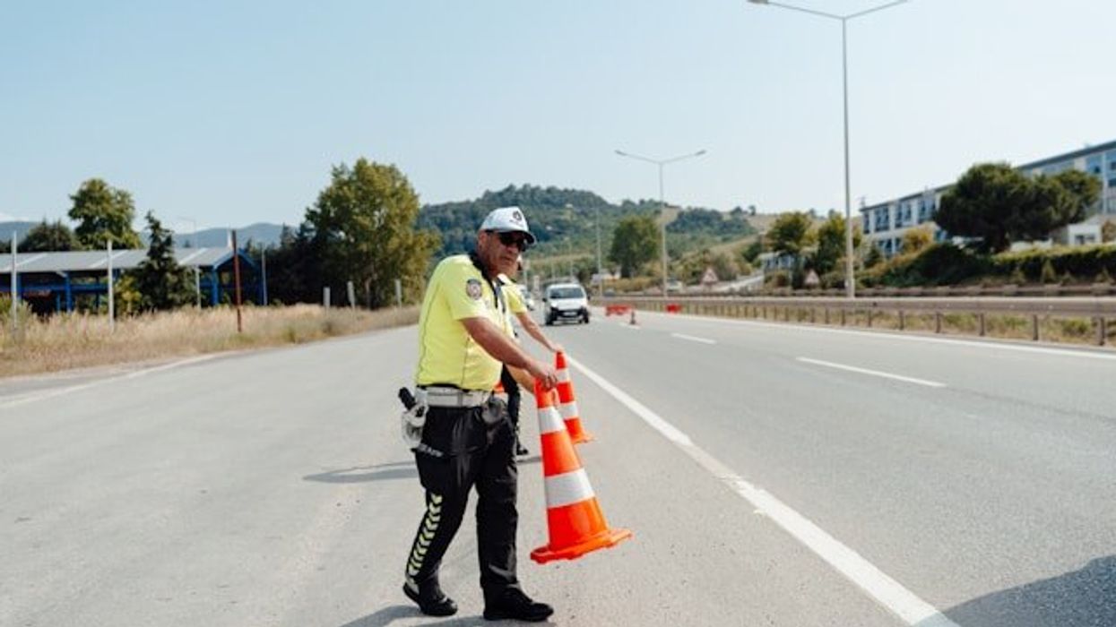 A road safety worker setting orange cones on a highway.