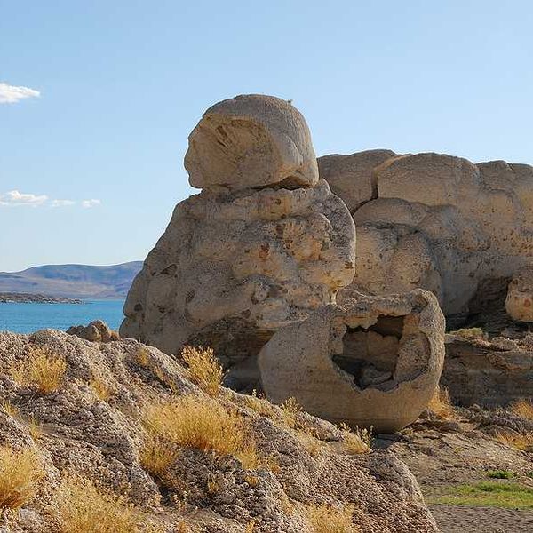 A rock formation in the desert with a lake in the background