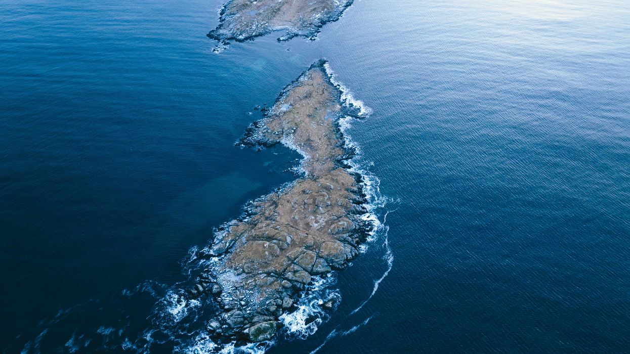 A rocky island in the middle of the ocean viewed from above