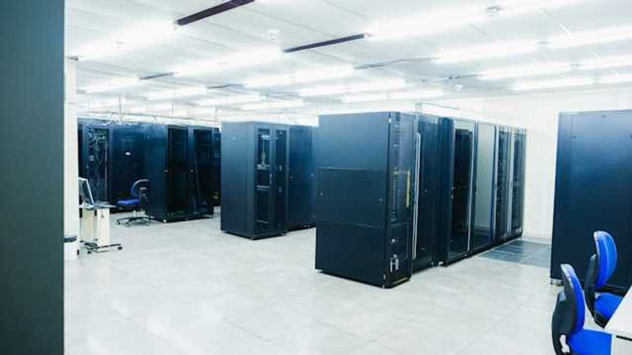A room full of black server cabinets under fluorescent lighting