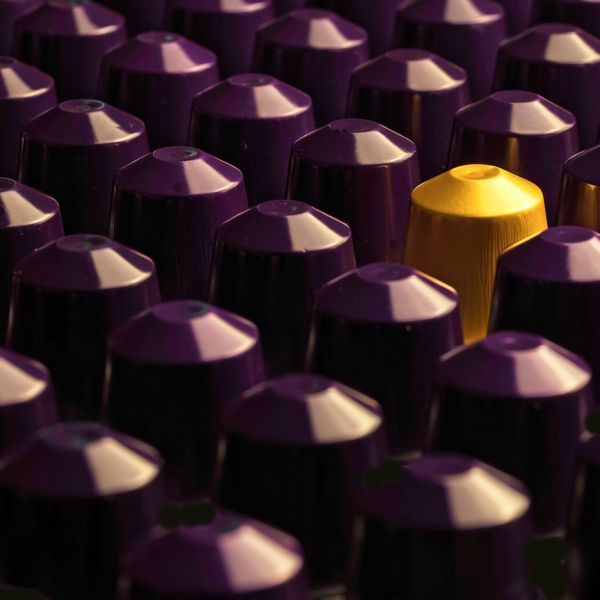 A row of brown and one yellow coffee pods