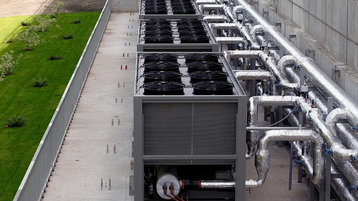 A row of data center cooling towers connected to a building with pipes