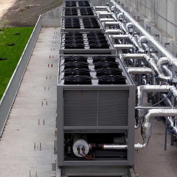 A row of data center cooling towers connected to a building with pipes