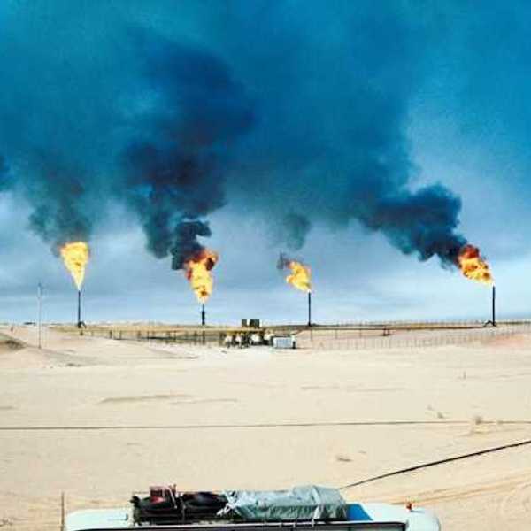 A row of gas towers flaring smoke and fire into the air
