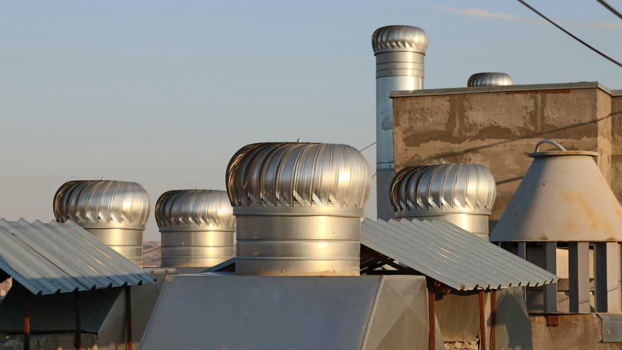 a row of metal chimneys on top of a building.