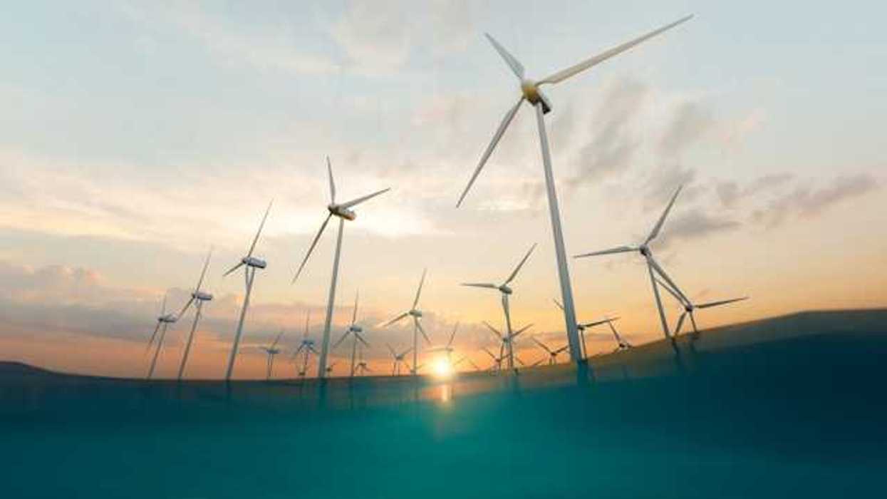 A row of offshore wind turbines with the setting sun in the background