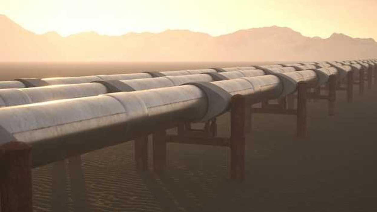 A row of pipelines stretching across a dry environment with mountains in the background