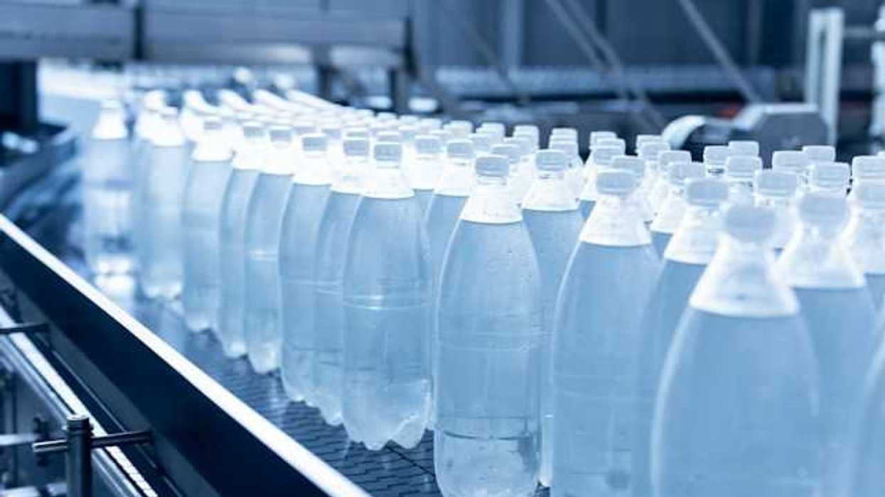 A row of plastic bottles with liquid in them on a conveyer belt