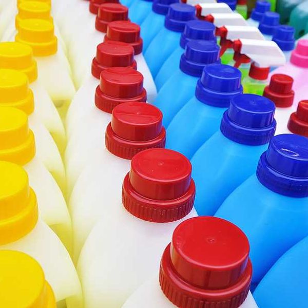 A row of plastic detergent bottles with multicolored lids