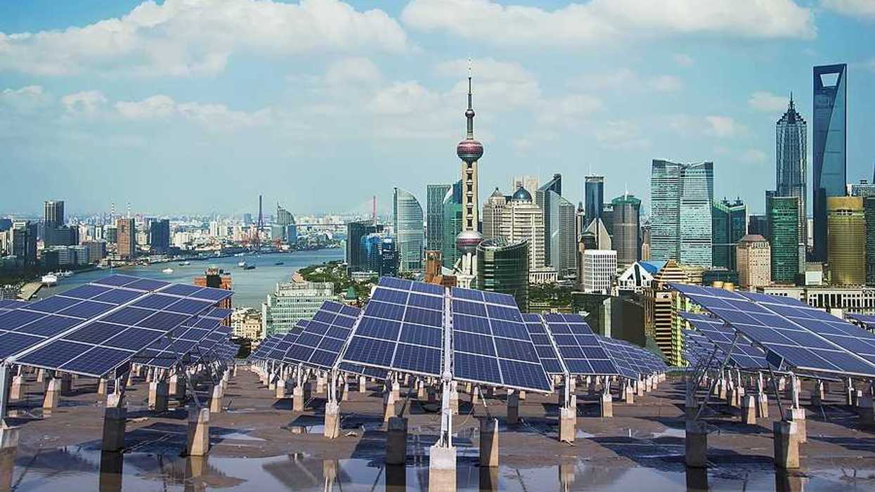 A row of solar panels with the city of Shanghai in the background