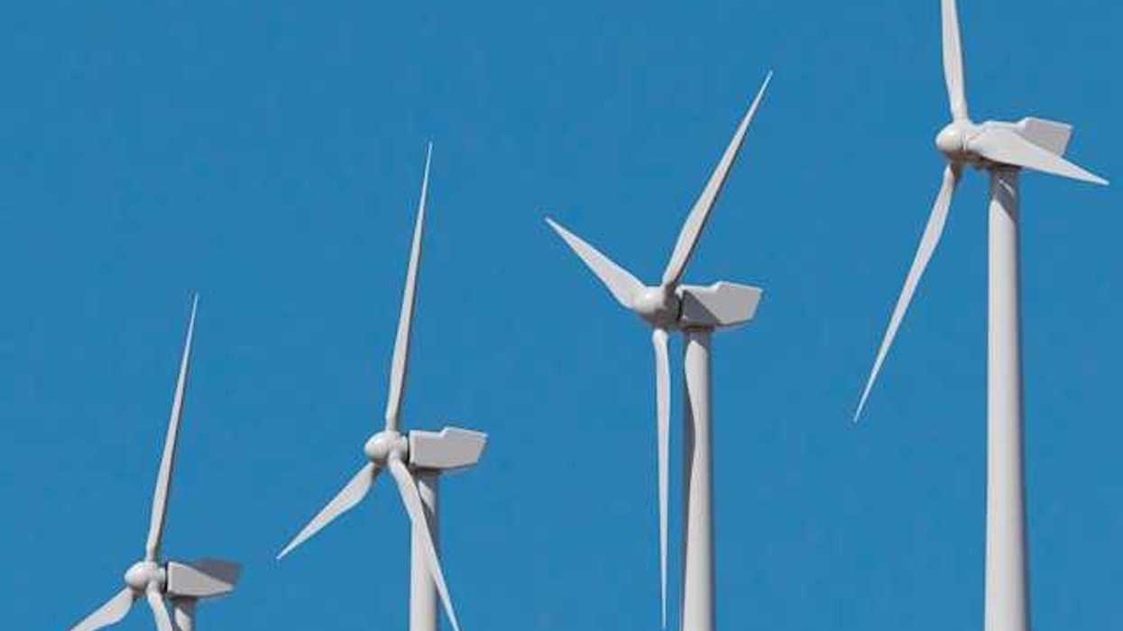 A row of wind turbines against a blue sky