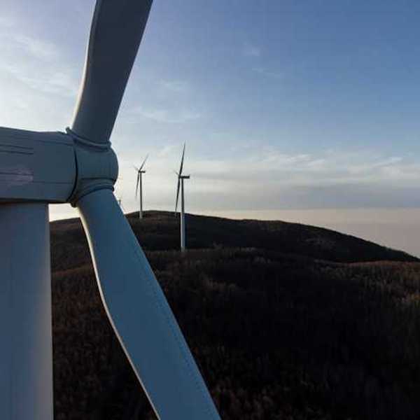 A row of wind turbines at dusk installed on rolling hills