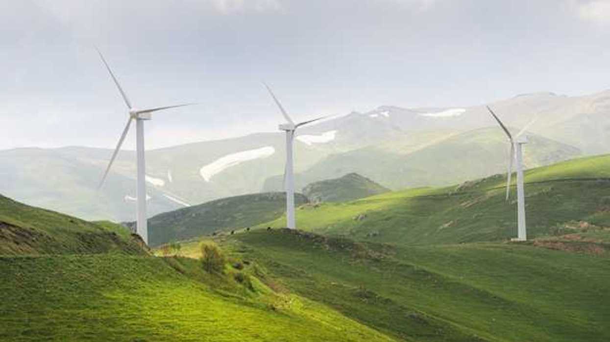 A row of wind turbines on green hills