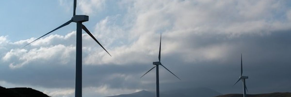 A row of wind turbines stretching across the hills.