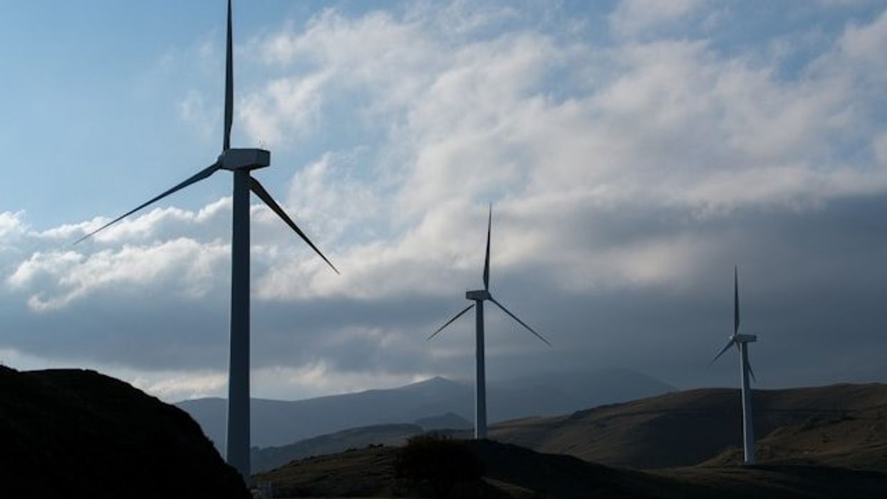 A row of wind turbines stretching across the hills.