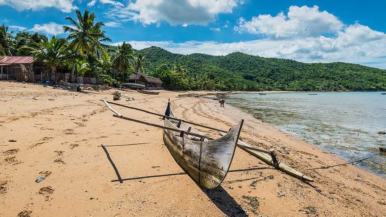 A rustic boat sitting on a beach beside the ocean