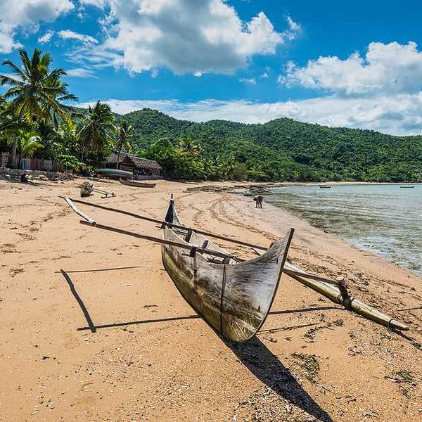 A rustic boat sitting on a beach beside the ocean