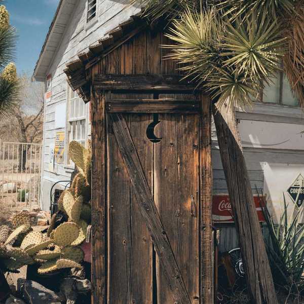 A rustic outhouse with a crescent moon in the door
