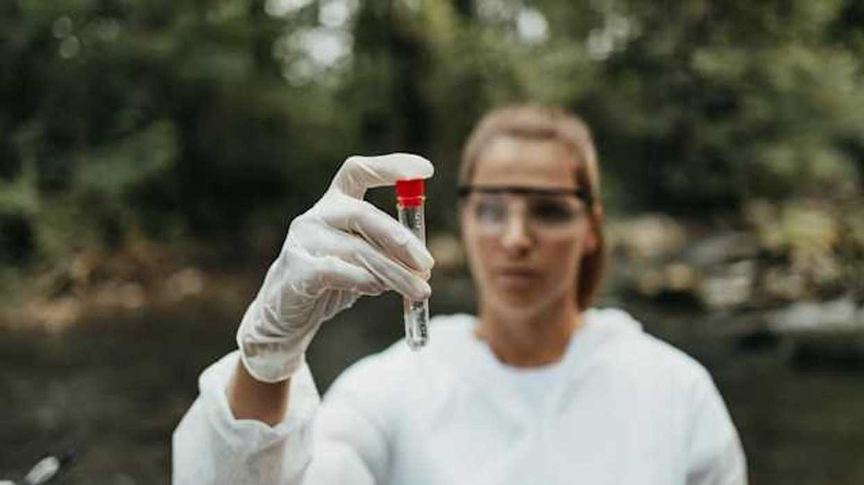 A scientist holding a water sample in a stream