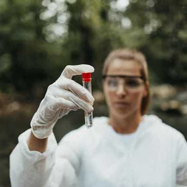 A scientist holding a water sample in a stream