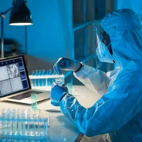 A scientist in a hazmat suit testing liquids in beakers