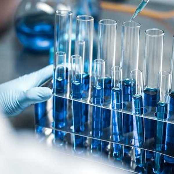 A scientist working with beakers filled with blue liquid