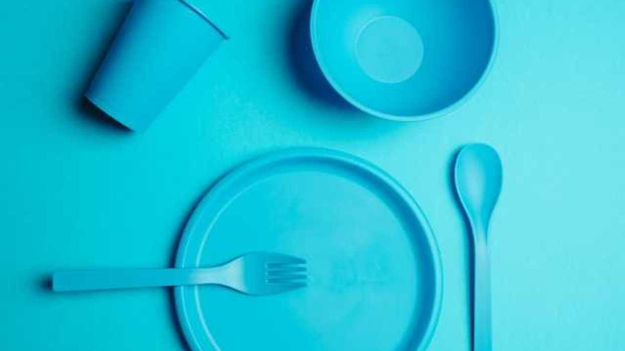 A set of plastic utensils and plates on a blue background