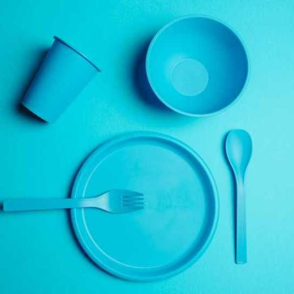 A set of plastic utensils and plates on a blue background