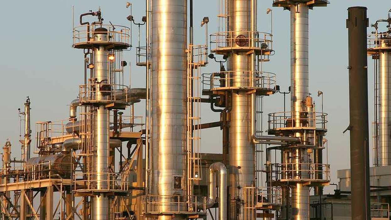A set of refinery smokestacks shining in the sun