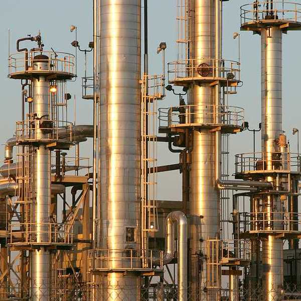 A set of refinery smokestacks shining in the sun